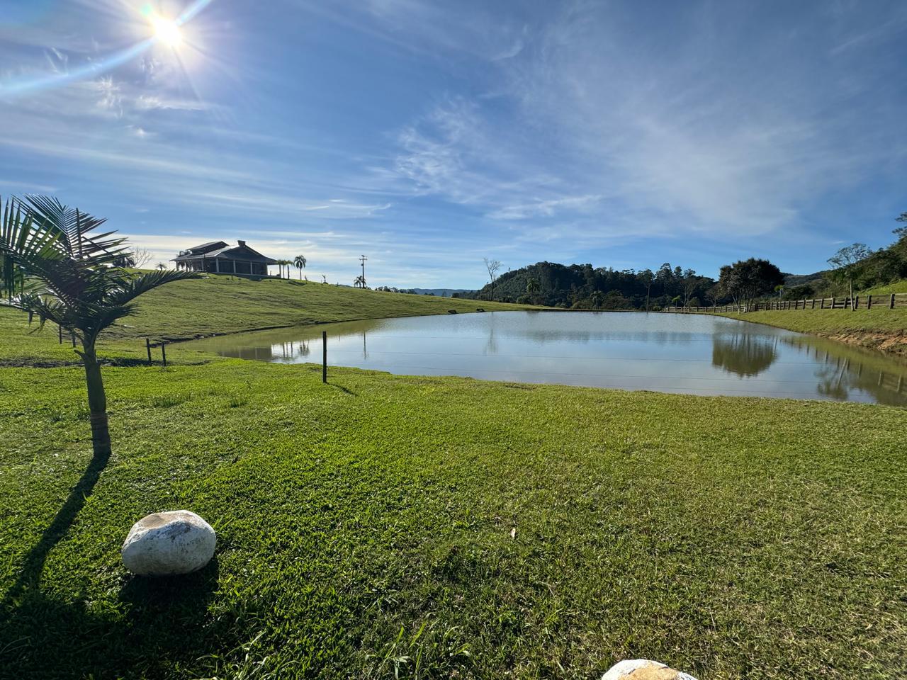 Açude com a casa ao fundo em dia de sol