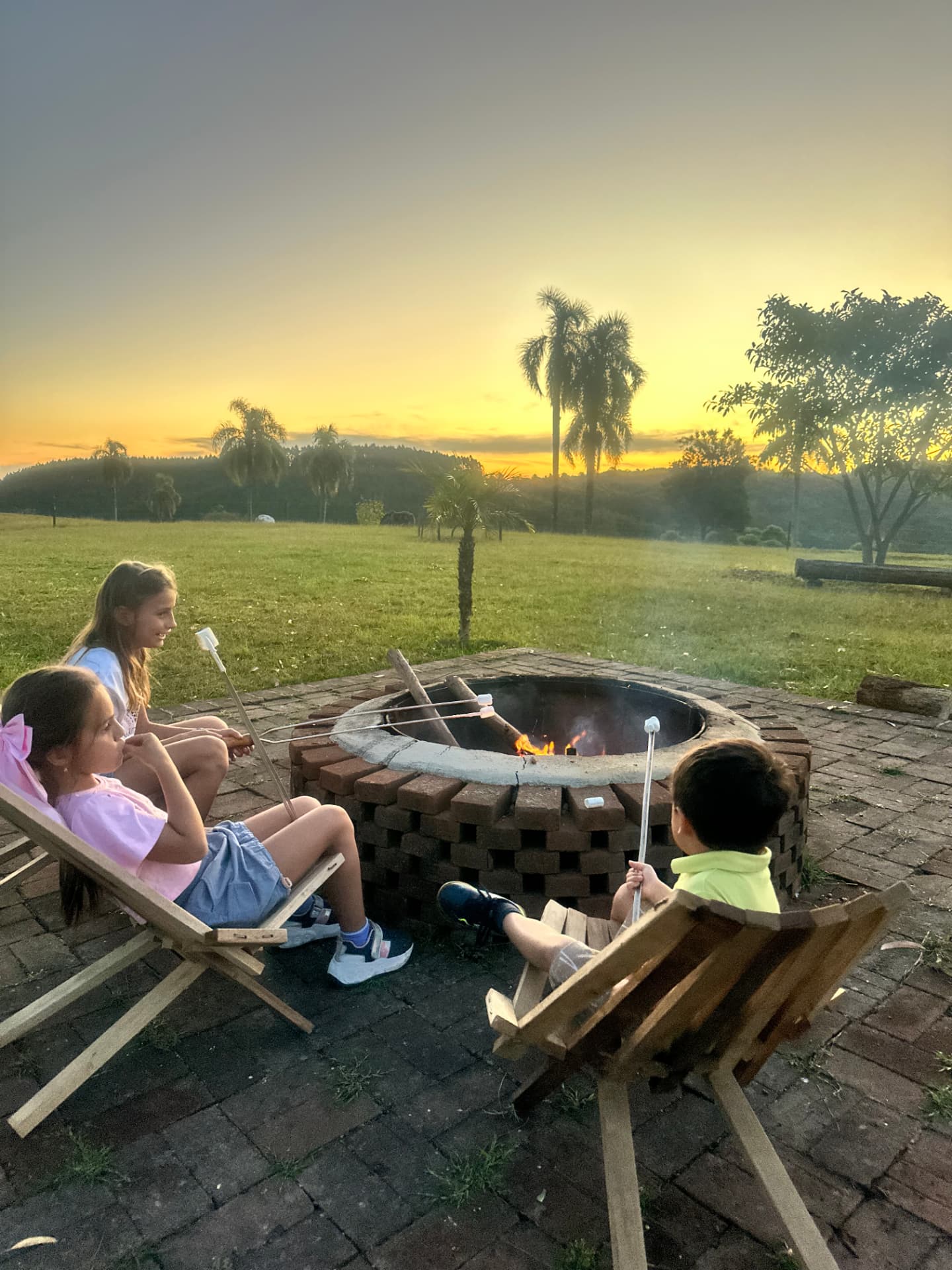 Crianças assando marshmallow na fogueira ao pôr do sol